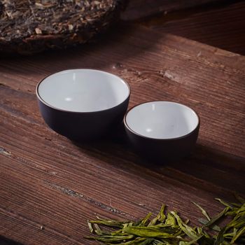 Ceramic tea cup, loose tea leaf on wood table