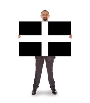 Smiling businessman holding a big card, flag of Cornwall, isolated on white