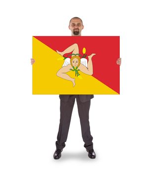 Smiling businessman holding a big card, flag of Sicily, isolated on white