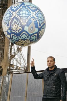 FRANCE, Paris: US artist Shepard Fairey, Obey's creator, poses on the Eiffel tower in Paris, on November 20, 2015, close to his 'Earth Crisis', a 2.3-ton globe displayed by as part of the organisation of the Conference on Climate Change COP21-CMP11.