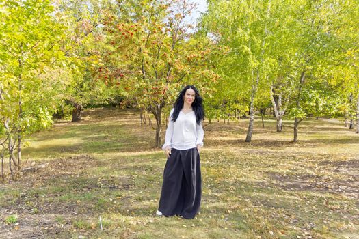 European woman with black hair walking in autumn park