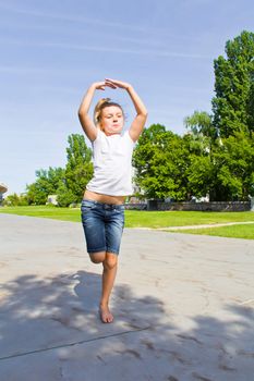 Cute girl with blond hair jumping on one leg