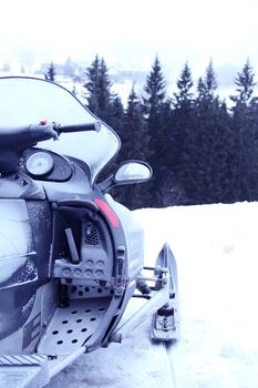 Side view of Snowmobile in winter mountains with forest