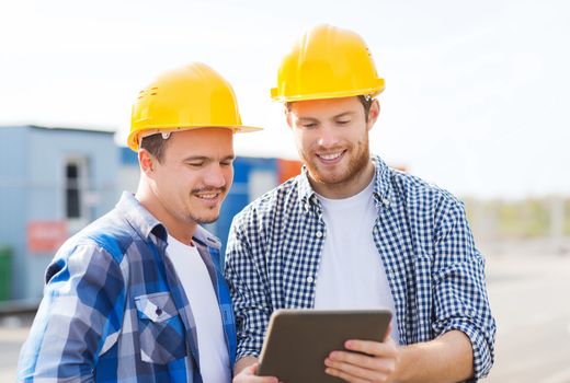 business, building, teamwork, technology and people concept - group of smiling builders in hardhats with tablet pc computer outdoors