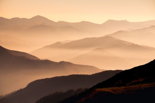 Landscape view of misty mountain hills at sunset with dramatic mood
