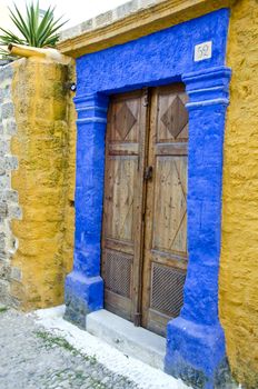 Antique doorway in Greek island painted yellow and blue. Architecture detail
