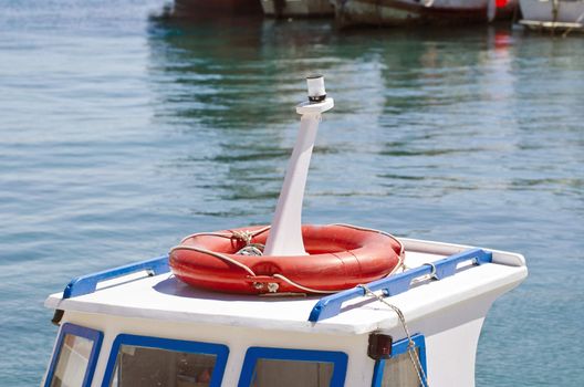 Roof of a boat with orange lifebuoy in the harbor