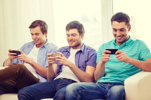 friendship, technology and home concept - smiling male friends with smartphones at home