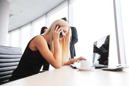 Young cute businesswoman talking on phone in office