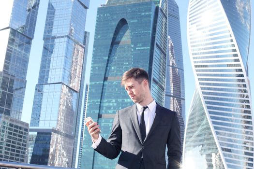 Businessman using smartphone on skyscraper background