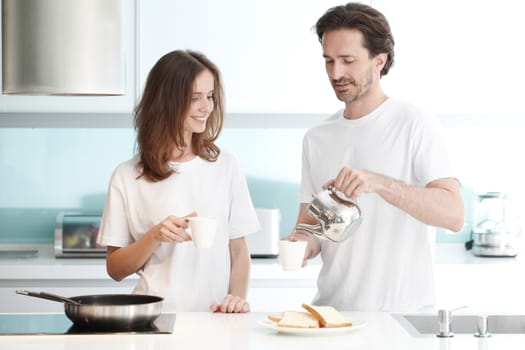 Happy couple cooking breakfast together in the kitchen