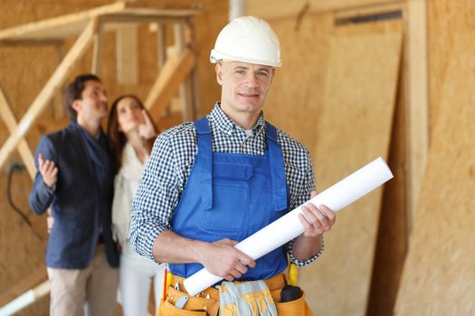 Foreman with design plans and young couple looking at new house