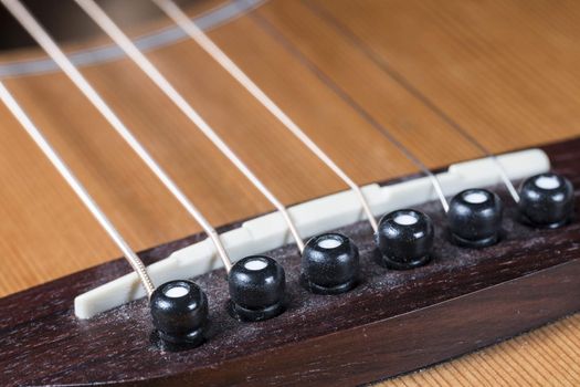 Guitar Saddle and Bridge close up on a steel string guitar.