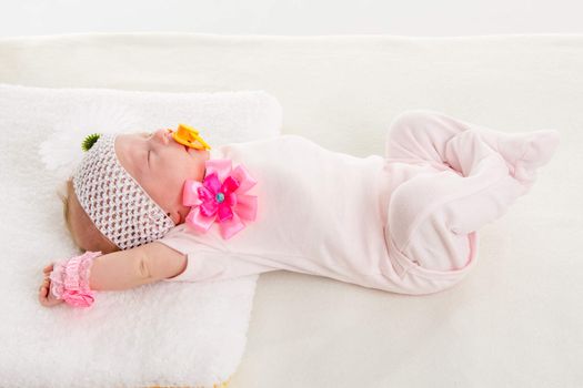 a two-month baby girl Europeans on the back with a bandage on his head with a flower lying on a soft bed