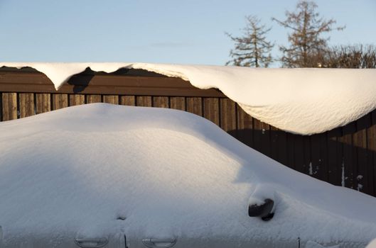 Snow Covered Car in front of building.