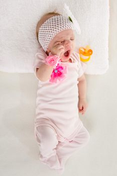 a two-month baby girl Europeans lies on his back with a bandage on his head with a flower