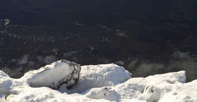 Snowy Rocks by Icy River in early winter.