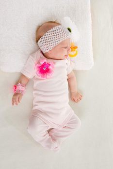 a two-month baby girl Europeans lies on his back with a bandage on his head with a flower
