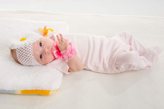 a two-month baby girl Europeans on the back with a bandage on his head with a flower lying on a soft bed