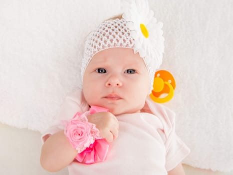 a two-month baby girl Europeans on the back with a bandage on his head with a flower lying on a soft bed