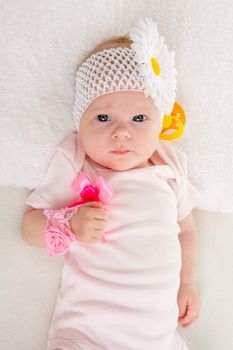 a two-month baby girl Europeans on the back with a bandage on his head with a flower lying on a soft bed