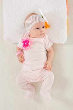 a two-month baby girl Europeans on the back with a bandage on his head with a flower lying on a soft bed