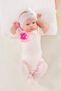 a two-month baby girl Europeans on the back with a bandage on his head with a flower lying on a soft bed