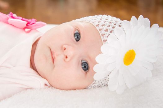 a two-month baby girl Europeans on the back with a bandage on his head with a flower lying on a soft bed
