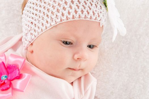 a two-month baby girl Europeans on the back with a bandage on his head with a flower lying on a soft bed