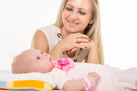a two-month baby lying on his back on the bed, sitting next to the child and mother looking at her