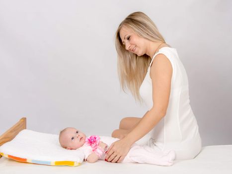 a two-month baby lying on his back on the bed, sitting next to the child and mother looking at her