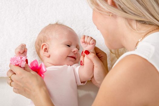 a two-month baby lying on his back on the bed, sitting next to the child and mother looking at her