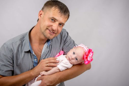 Young dad sitting on a bed and holds her two-month baby daughter