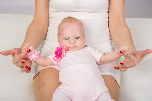 a two-month baby lying on her back on her mother's lap and looking at her