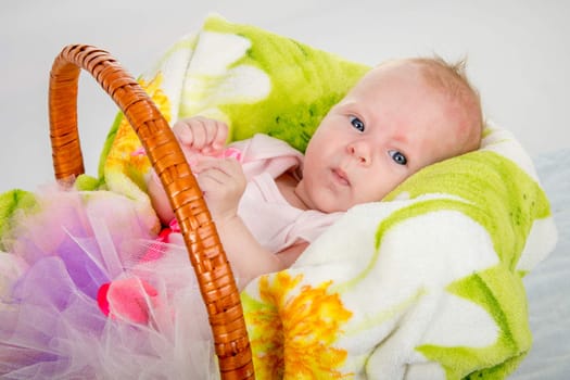a two-month baby girl Europeans lies in a basket on a soft blanket