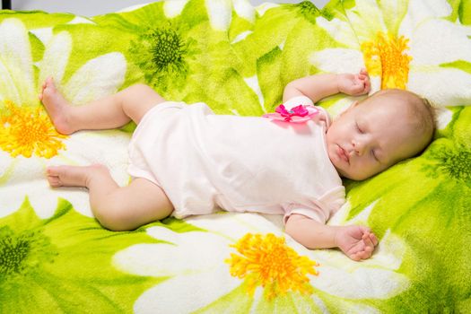 a two-month baby girl Europeans lies on a soft bed on colored coverlet