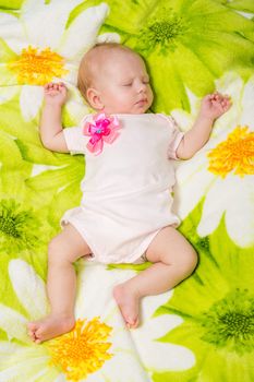a two-month baby girl Europeans lies on a soft bed on colored coverlet