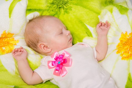 a two-month baby girl Europeans lies on a soft bed on colored coverlet