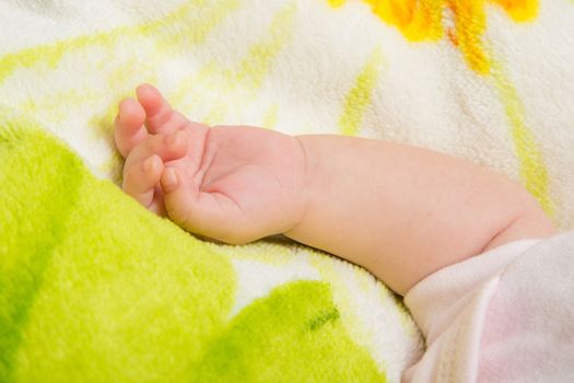 a two-month baby girl Europeans lies on a soft bed on colored coverlet