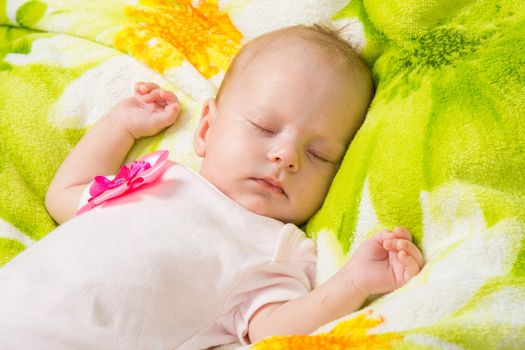 a two-month baby girl Europeans lies on a soft bed on colored coverlet