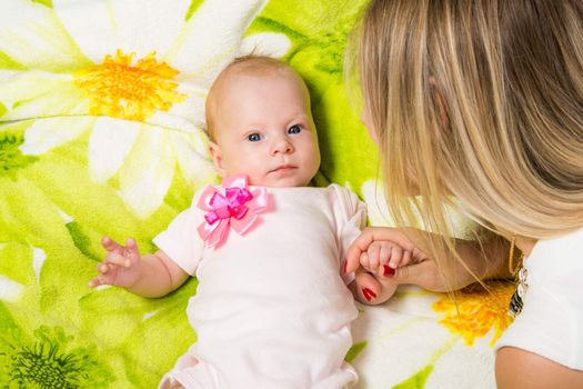 a two-month baby lying on his back on the bed, sitting next to the mother and the baby looks at her