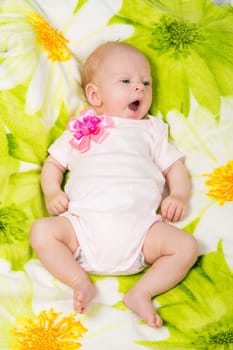 a two-month baby girl lying on the bed Europeans on colored coverlet