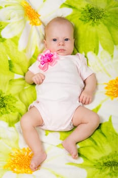 a two-month baby girl lying on the bed Europeans on colored coverlet