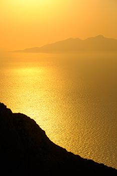 Landscape view of beautiful colorful sunrise above the ocean with horizon and distant islands, Santorini, Greece