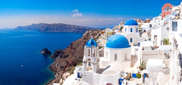 Panoramic scenic view of beautiful white houses and blue domes in Oia, Santorini, Greece