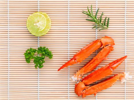 Boiled crab claws with lime and parsley on bamboo background.