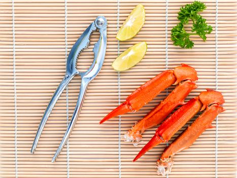 Boiled crab claws with lime and parsley on bamboo background.