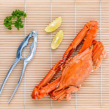 Boiled crab claws with lime and parsley on bamboo background.