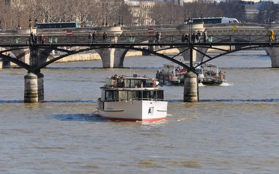 PARIS, FRANCE - CIRCA MARCH 2010: Sightseeing boats on the river Seine. The first bridge is the Pont des Arts, the second one is Pont Neuf.