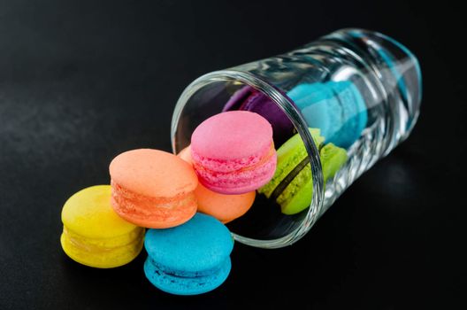 Colorful macaroons in glass on over black background